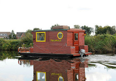 Hausboot in Fahrt - Kahn mit Holzaufbau / Holzhaus und Aussenbordmotor auf der Doveelbe vor Hamburg Reitbrook.