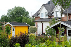 Gärten im Neubauviertel von Hamburg Langenbek - bunte Gerätehäuser aus Holz.