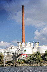 Industriearchitektur im Hamburger Stadtteil Wilhelmsburg - Raffinerieanlage mit Tanks und hohem Schornstein am Ufer der Süderelbe - Schild Tankhafen.