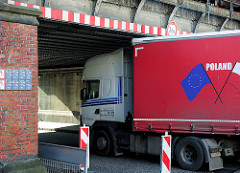 Lastwagenverkehr im Hafengebiet von Hamburg Harburg; ein polnischer LKW fährt knapp unter einer 3,80 hohen Eisenbahnbrücke hindurch.