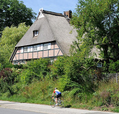 Historisches Fachwerkgebäude - Dach mit Reet gedeckt; Fahrradfahrter auf dem Fussweg - Bilder aus dem Hamburger Stadtteil Wilstorf.