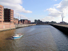 Ein Barkasse fährt im Sandtorhafen; rechts Bürogebäude, dahinter die Speicherstadt + das Kesselhaus; rechts das Kraftwerk Hafencity (2003)