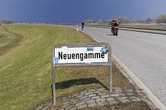 Stadtteilschild von Hamburg Neuengamme. Motorradfahrer auf der Elbdeichstrasse.