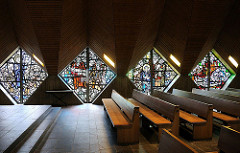 Sitzbänke und leuchtende Glasmosaikfenster der Saseler Lukaskirche.