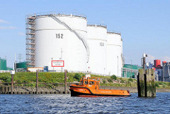 Hohe Tanks am Ufer der Wilhelmsburger Rethe; ein Festmacherboot an hat an den Holzdalben angelegt.