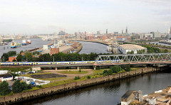 Eisenbahnbrücke über den Billhafen / Oberhafenkanal. In der Bildmitte der Baakenhafen; ein Frachter liegt am Versmannkai; dahinter eine Baustelle der Hafencity bei der Versmannstrasse.