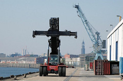 Teleskop Container Spreader am Ende des Versmannkais des Hamburger Baakenhafens. Im Hintergrund die Lagerschuppen des Hafenkais und der Turm des Michels, dem Hamburger Wahrzeichen. (2005)