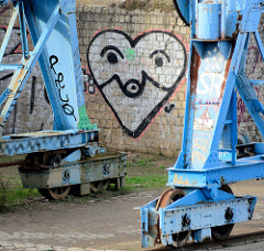 Graffiti - Herz auf der Ziegelmauer; Laufrollen auf Schienen am Billehafen in Hamburg Rothenburgsort.