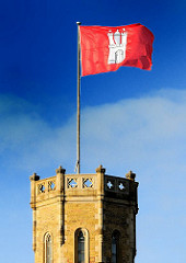 Die Hamburg Fahne flattert im Wind auf dem Turm der Alten Post.