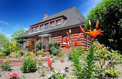 Backsteinhaus mit blühenden Blumen im Vorgarten - Einzelhaus in Hamburg Wilstorf.