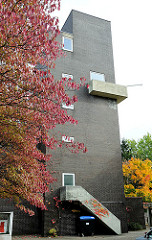 Kirchturm der Dietrich Bonhoeffer Kirche in Hamburg Dulsberg Süd - Backsteinkirche / Ziegelfassade; Herbstbaum mit roten Blättern.