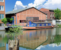 Hausboot auf dem Veringkanal von Hamburg Wilhelmsburg - altes Lagergebäude am Kanal.