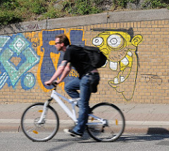 Graffiti auf einer Ziegelwand - Radfahrer auf der Strasse.