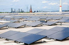 Solaranlagen auf dem 29 000 m² großen Dach des HHLA Logistikzentrums in Hamburg Altenwerder. Im Hintergrund der Kirchturm der St. Gertrudkirche des verlassenen Dorfes Altenwerder und rechts der Sockel der Windkraftanlage.