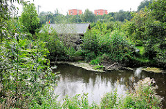 Blick über den Seevekanal zu Hochhhäusern von Hamburg Rönneburg; am Kanalufer Lauben von Schrebergärten.