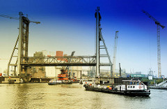 Hochgefahrene Rethehubbrücke in Hamburg Wilhelmsburg - zwei Schiffe fahren in die Rethe ein - Arbeitsschiffe und Kräne; Bau der neuen Rethebrücke.