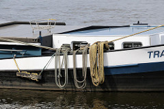 Binnenschiff am Ufer der Süderelbe von Hamburg Harburg - die Taue liegen aufgeschossen über der Bordwand des Schiffs.