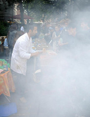 Kulinarische Angebote -  Fest auf der Schanze - von einem Grill steigt dichter Qualm auf.