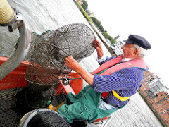 Der Fischer holt die ausgelegte Reuse in seine kleine Jolle.