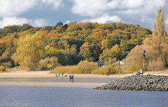 Herbst am Hamburger Elbufer - herbstlich gefärbte Bäume am Elbhang; Spaziergänger am Sandstrand in der Sonne.