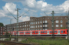 Wohnblocks an der S-Bahnstrecke - Hamburg Veddel, fahrender Zug vor den Fenstern der Wohnungen.