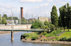 Blick von den Norderelbbrücken auf den Elbpark Entenwerder in Hamburg Rothenburgsort. Eine Fussgängerbrücke führt über den Haken, einem ehem. Hafenbecken zum Elbpark - im HIntergrund die Netze der Golfanlage und der historische Wasserturm.