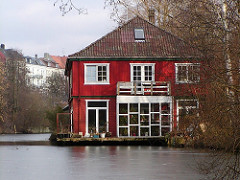 Rotes Hausboot am Ufer des Isebekkanals - Motive aus dem Bezirk Hamburg Eimsbüttel.