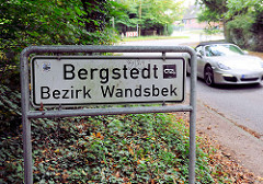 Ortsschild Hamburg Bergstedt, Bezirk Wandsbek; fahrender Porsche.
