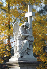 Trauernder Engel / Trauerengel auf einem Grabstein des Friedhofs St. Johannis Kirche in Hamburg Neuengammme. Herbstlaub im Hintergrund.