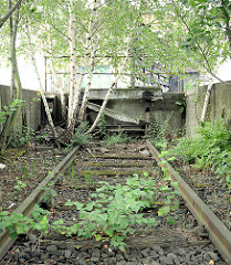 Bahngleis der Güterbahn / Hafenbahn im Hamburger Oberhafen - das Gleis ist stillgelegt, der Prellbock zerfallen; Birken wachsen bei den Gleisen.