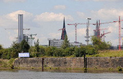 Alte Kaimauer im Moldauhafen - Namensschild den historischen Hafenbeckens - im Hintergrund Kräne der Baustelle Hafencity.