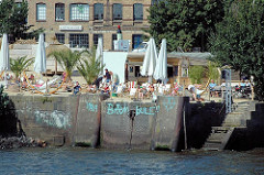 Beachclub an der Großen Elbstraße  - Menschen in Liegestühlen in der Sonne an der Elbe - Inschrift an der Kaimauer Viva Bambule (2005)