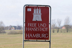 Schild Freie und Hansestadt Hamburg, weisses Hamburger Wappen auf rotem Grund.