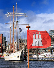 Fahne von Hamburg  - Flagge der Hansestadt an der Elbe. Segelschiff im Hintergrund.