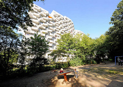 Hochhaus der Siedlung Osdorfer Born in Hamburg Osdorf - Kinderspielplatz unter Bäumen.