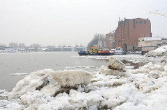 Eisschollen in der Billwerder Bucht von Hamburg Rothenburgsort - historische Industriearchitektur am Ufer. Im Hintergrund das Billwerder Sperrwerk - Hochwasserschutz in Hamburg.