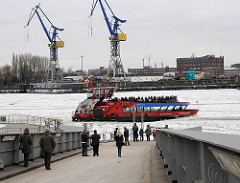Eine Hafenfähre legt von den St. Pauli Landungsbrücken ab und fährt durch die Eisschollen auf der Elbe Richtung Hamburg Altona.