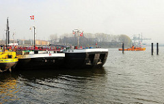 Binnenschiffe liegen im Finkenwerder Vorhafen - eine Barkasse fährt im Hintergrund Richtung Saugerstation in Hamburg Finkenwerder.