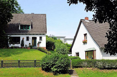 Einzelhäuser mit weisser Fassade und Spitzdach in Hügellandschaft - Hausbau am Berg; Bilder aus Hamburg Eißendorf.