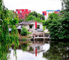 Schrebergartenlaube am Ufer des Assmannkanals - Containerstapel im Hintergrund in Hamburg Wilhelmsburg.