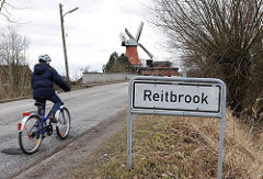 Stadtteilschild Reitbrook - Fahrrad auf der Strasse - Mühle von Hambug Reitbrook im Hintergrund.