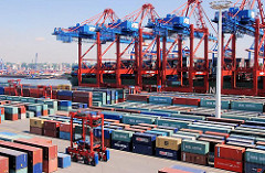 Frachtschiff unter den Containerbrücken am Kai des TErminal Eurogate - Portalhubwagen im Containerlager in Hamburg Waltershof.