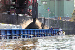Der Frachtraum des Binnenschiffs ist mit Schüttgut gefüllt - das Schiff liegt tief im Wasser des Sandauhafens in Hamburg Altenwerder.