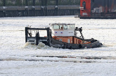 Schubschiff als Eisbrecher im Hamburger Hafen - eisbedeckte Elbe in Hamburg; das Schiff schiebt die Eisschollen vor sich her.