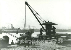 Handkran am Sandtorhöft; eine Ladung Kohlensäcke wurde an Land gebracht und liegt auf einer Waage - Kohlenträger am Kai.  ( ca. 1905 )