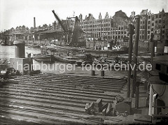 Mit Hilfe von Schuten und Barkassen wird eine durch Kriegseinwirkungen ins Hafenwasser gestürzte Lokomotive der Hafenbahn im Sandtorhafen zum Schwimmkran geschleppt. Am Sandtorkai liegen Arbeitsboote. (1948)