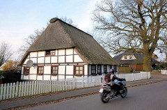 Reetdachkate mit Fachwerk; Motorradfahrer - Pinneberger Strasse in Quickborn.