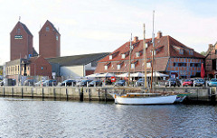 Zum Restaurant umgebautes altes Speichergebäude am Hafen von Neustadt in Holstein; Silotürme - Segelschiff am Kai.