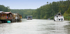 Bootshäuser am Müritz-Havel-Kanal - Sportboot und Hausboot in Fahrt; Wälder bis an das Ufer.