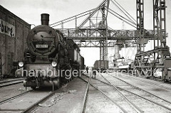 Eine Güterzugtenderlokomotive der Reihe 93 1008 rangiert auf den Gleisen am Harburger Seehafen - Güterwagen stehen am Kai neben einem Kohlenfrachter, dessen Ladung gerade gelöscht wird. (ca. 1938)